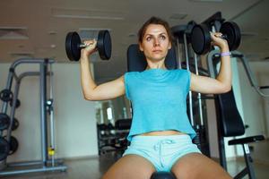 Woman with dumbbells in the gym doing exercises photo