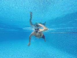 Beard man with glasses swimming under water in the pool photo