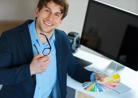 Man looking to a color paint palette at home office photo
