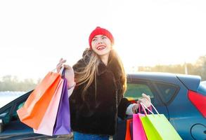 Smiling Caucasian woman holding her shopping bag near the car photo