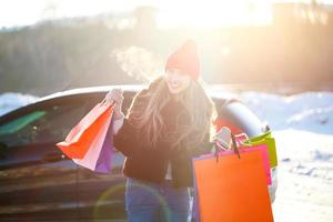 Smiling Caucasian woman holding her shopping bag near the car photo