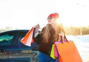 Smiling Caucasian woman holding her shopping bag near the car photo