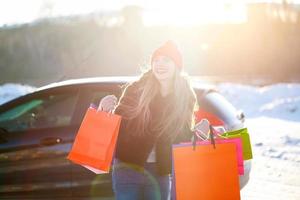 Smiling Caucasian woman holding her shopping bag near the car photo