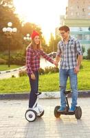 Young couple riding hoverboard - electrical scooter, personal eco transport, gyro scooter, smart balance wheel photo