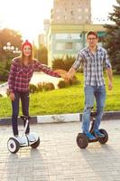 Young couple riding hoverboard - electrical scooter, personal eco transport, gyro scooter, smart balance wheel photo