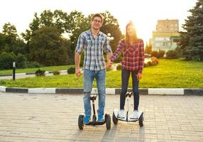 Young couple riding hoverboard - electrical scooter, personal eco transport, gyro scooter, smart balance wheel photo