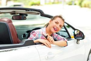 joven bonito mujer sentado en un convertible coche con el llaves en mano foto
