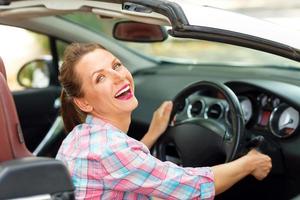 Young beautiful woman sitting in a convertible and is going to start the engine photo