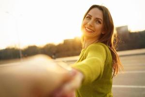 Follow me - happy young woman pulling guy's hand - hand in hand walking on a bright sunny day photo