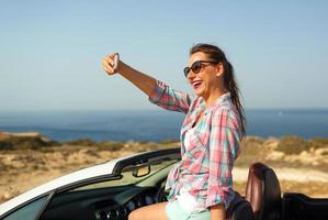 mujer en Gafas de sol haciendo yo retrato sentado en el cabriolé foto