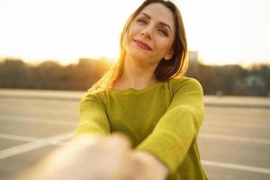 Happy young woman pulling guy's hand - hand in hand walking on a bright sunny day photo