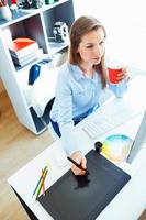 Woman drawing something on graphic tablet at the home office photo