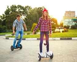 Young couple riding hoverboard - electrical scooter, personal eco transport, gyro scooter, smart balance wheel photo