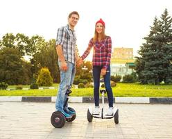 Young couple riding hoverboard - electrical scooter, personal eco transport, gyro scooter, smart balance wheel photo