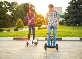 Young couple riding hoverboard - electrical scooter, personal eco transport, gyro scooter, smart balance wheel photo