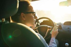contento mujer usos un navegador en un teléfono inteligente mientras conducción un coche foto