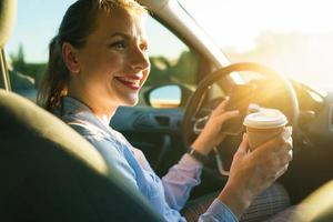 Young businesswoman sending a text message and drinking coffee in a car photo