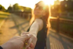 Follow me - happy young woman pulling guy's hand - hand in hand walking on a bright sunny day photo