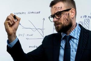 Man draws various growth charts, calculating prospects for success in a modern glass office photo