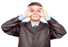 Businessman making binoculars with hands and looking through photo