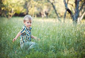 A cute little baby boy sit in the grass photo