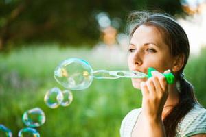 Girl blowing soap bubbles in the park photo