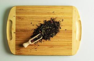 A mixture of black and green tea with rose petals close-up. Background of tea on a wooden board. photo