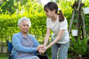 Caregiver help and care Asian elderly woman use walker with strong health while walking at park in happy fresh holiday. photo