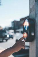 safety on the crossing street light, hand pressing pedestrian light for cross the road photo