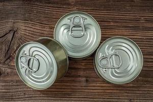 Tin cans with food on dark rustic wooden background. photo