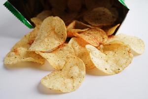 papas fritas en bolsa abierta, delicioso condimento de barbacoa picante para crips, refrigerio frito en rodajas finas comida rápida en bolsa abierta. foto