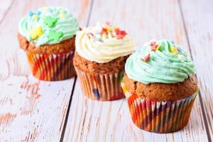 Colorful cupcakes on a white wooden background photo