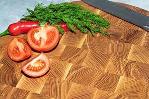 Wooden board for cutting handmade products with chopped vegetables. On a light background. photo