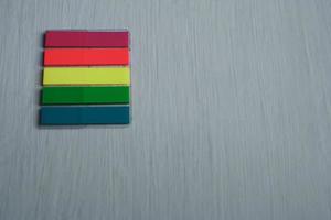 A set of colored bookmarks lies on a table horizontally on a light painted surface. photo