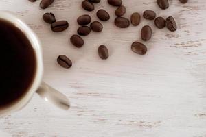 Flat view. Half a coffee cup with coffee and scattered coffee beans on a white background. Place for your text. photo