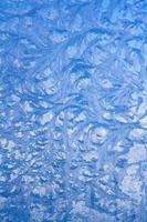 Winter pattern on glass. Drawing on a frozen window. Vertical. photo