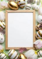 Blank picture frame surrounded by Easter eggs and tulip flowers on green background photo