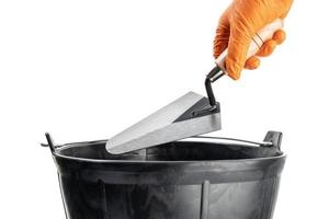 Hand Holding a Trowel over a mason bucket isolated on White Background. Copy space photo