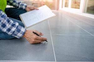 inspector or engineer is inspecting construction check tiled floor. Engineers and architects or contactor count materials for construction. Building, check, insurance house, quality, foreman. photo
