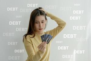 Stressed and headache asian woman with large bills or invoices no money to pay to expenses and credit card debt. shortage, Financial problems, mortgage, loan, bankruptcy, bankrupt, poor, empty wallet photo