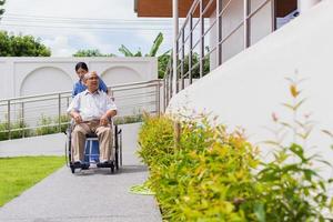 Nursing Home Care concept. asian Young nurse disabled elderly man. Nurse, care home and elderly man with disability in a wheelchair in an outside medical facility. photo