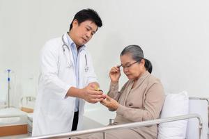 asiático masculino médico explicando medicina a mayor hembra paciente en hospital. foto