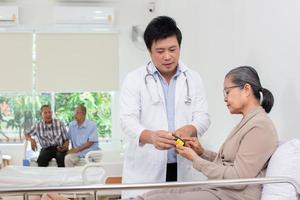 Asian male doctor explaining medicine to elderly female patient in hospital. photo