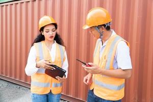 Female Asian engineer and foreman engineer loading containers from cargo ship for export. There is a container in the background. photo