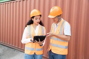 Female Asian engineer and foreman engineer loading containers from cargo ship for export. There is a container in the background. photo