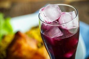 Tasty dish of chicken thigh with rice and lettuce and a glass of juice with ice photo