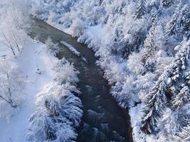View from a height to a winter landscape - a mountain river surrounded by a coniferous forest