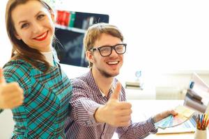 Beautiful young woman and man with thumb up in office photo