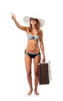 Full length portrait of a beautiful young woman posing in a bikini, hat and sunglasses with a suitcase in hand on white photo