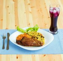 Dishes from turkey meat with rice and salad leaves and a glass of juice with ice photo